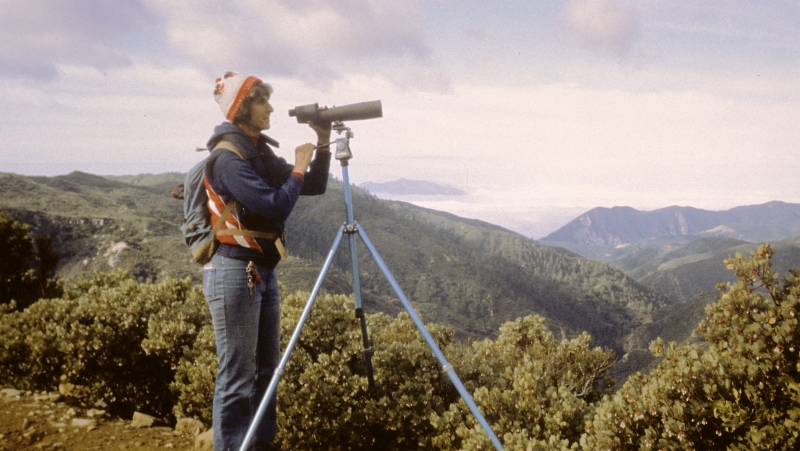 Woman biologist using telescope in the mountains