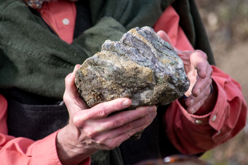 A gnarly-looking rock that almost looks like a giant moldy chunk of blue cheese, held in the gnarled hands of a famous local paleontologist
