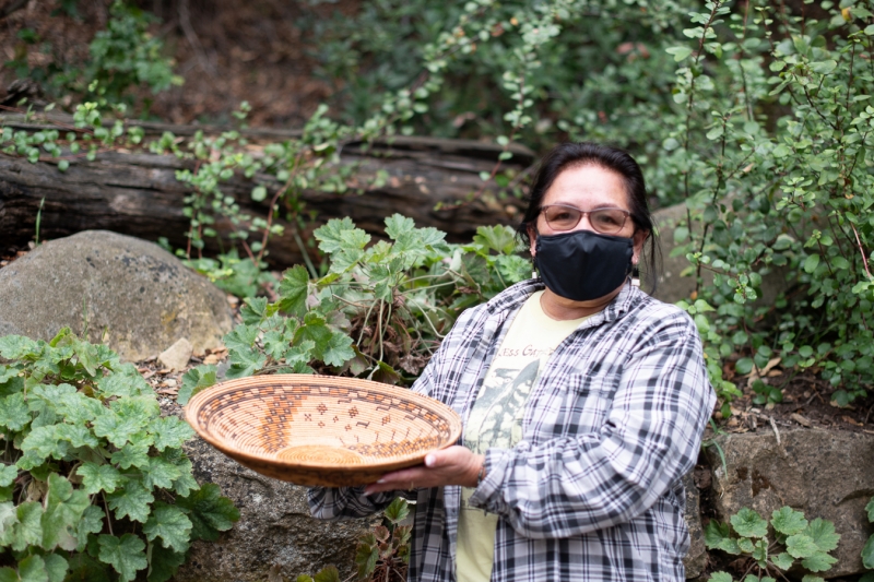 A dark-haired woman with glasses gently holds a beautiful basket. She's looking at the camera.