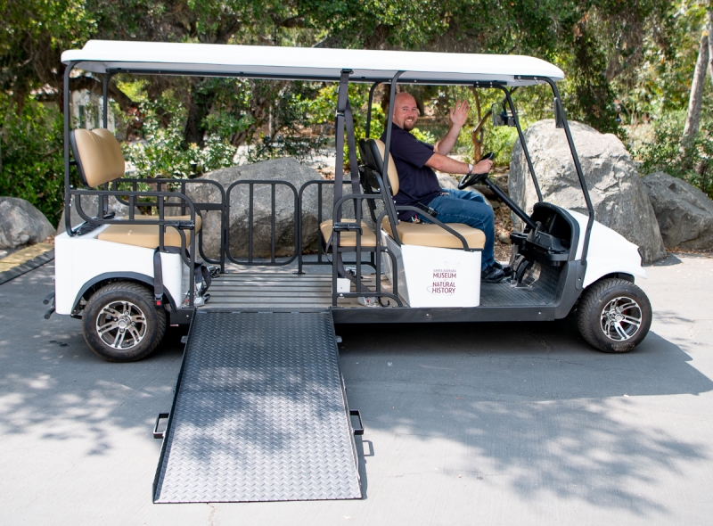 Jill's cart, an electric cart with wheelchair ramp. A smiling man is in the driver's seat.