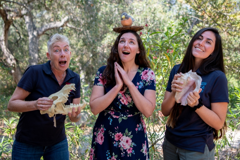 Three educators strike goofy poses with natural props