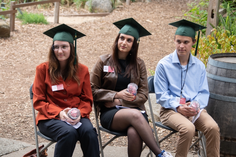 Three young people in green mortarboard hats, ready for graduation