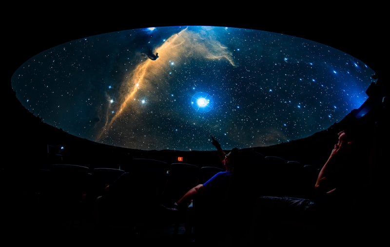 Looking up at the screen of the planetarium to see stars and nebulae
