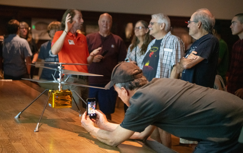 Man photographing a model of the Ingenuity helicopter on his cell phone