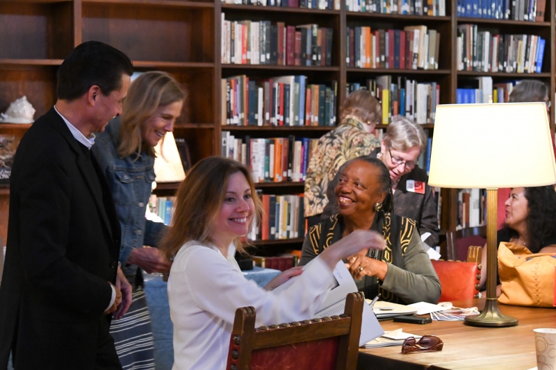 Smiling poet at the center of a library scene with people and books