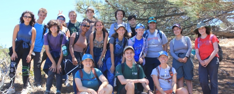 A big group of smiling teens pose for a photo with Torrey Pines